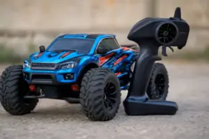 Blue and black HSP RC monster truck with large tires and a black transmitter on concrete.